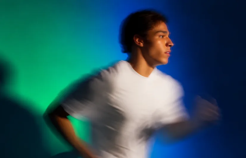 Person moving through an emerald and cobalt light composition